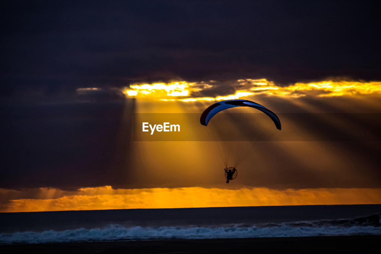 PERSON PARAGLIDING AGAINST SKY DURING SUNSET