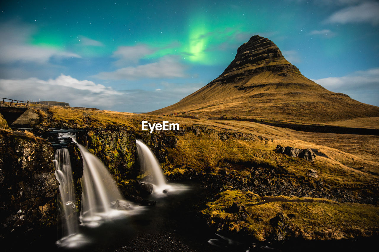 Scenic view of waterfall against sky with aurora borealis