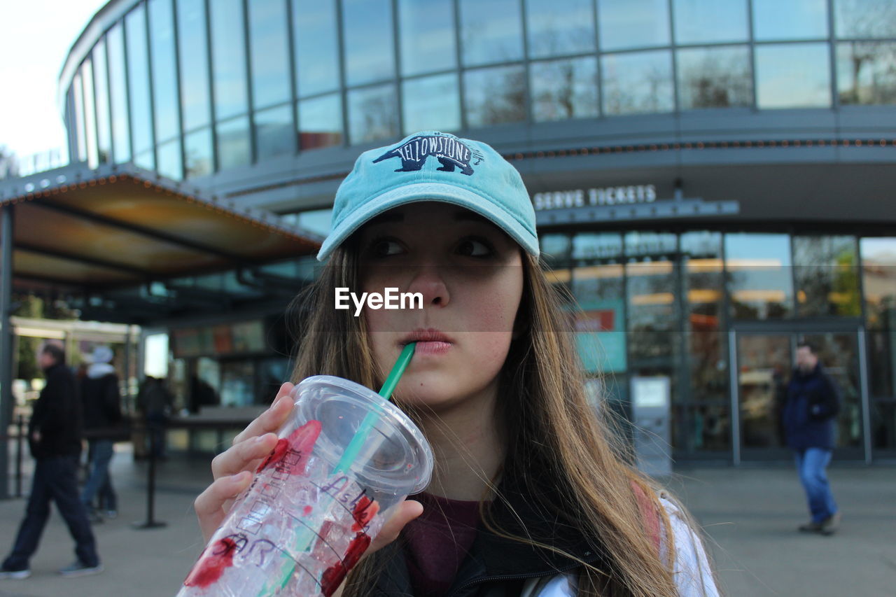 CLOSE-UP OF A YOUNG WOMAN DRINKING GLASS OUTDOORS