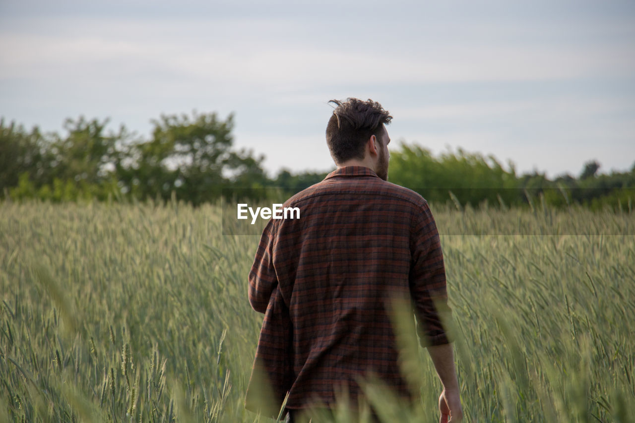 Rear view of young man walking on field