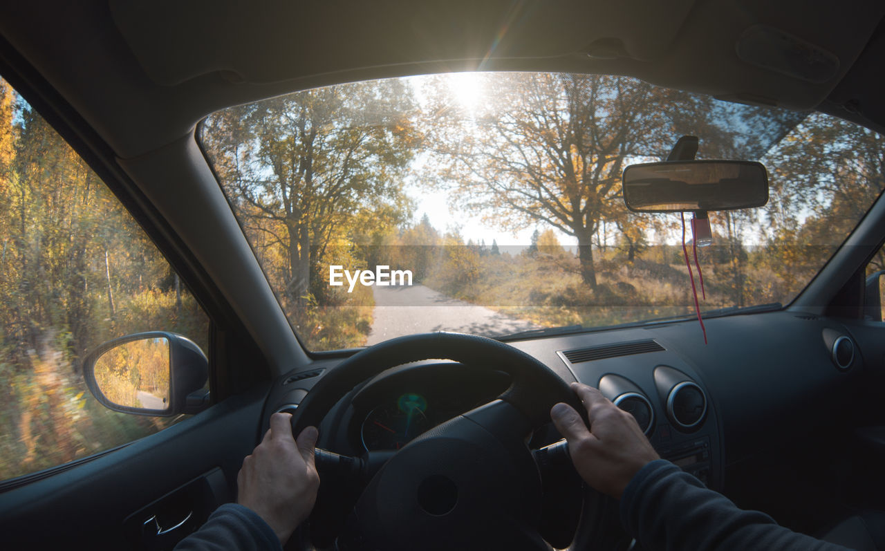 A man drives a car on a forest road in the autumn forest. point of view