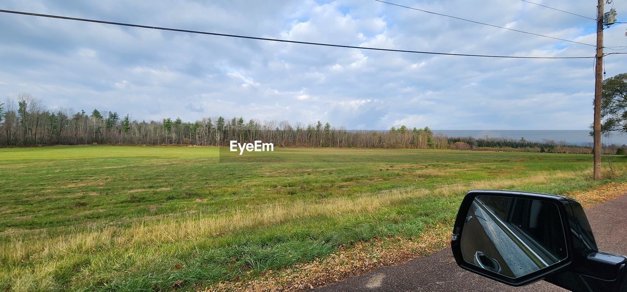 transportation, sky, plant, cloud, landscape, rural area, road, cable, nature, mode of transportation, land, grass, electricity, technology, tree, environment, road trip, rural scene, motor vehicle, power line, car, mirror, field, no people, scenics - nature, day, electricity pylon, land vehicle, travel, non-urban scene, prairie, vehicle, green, beauty in nature, outdoors, country road, infrastructure, plain, tranquility, highway, tranquil scene, meadow, natural environment