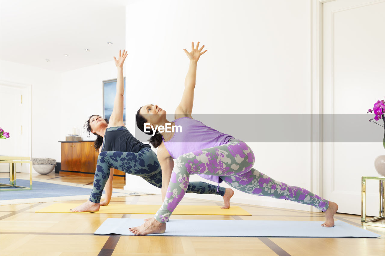 Side view of women exercising on mat at home