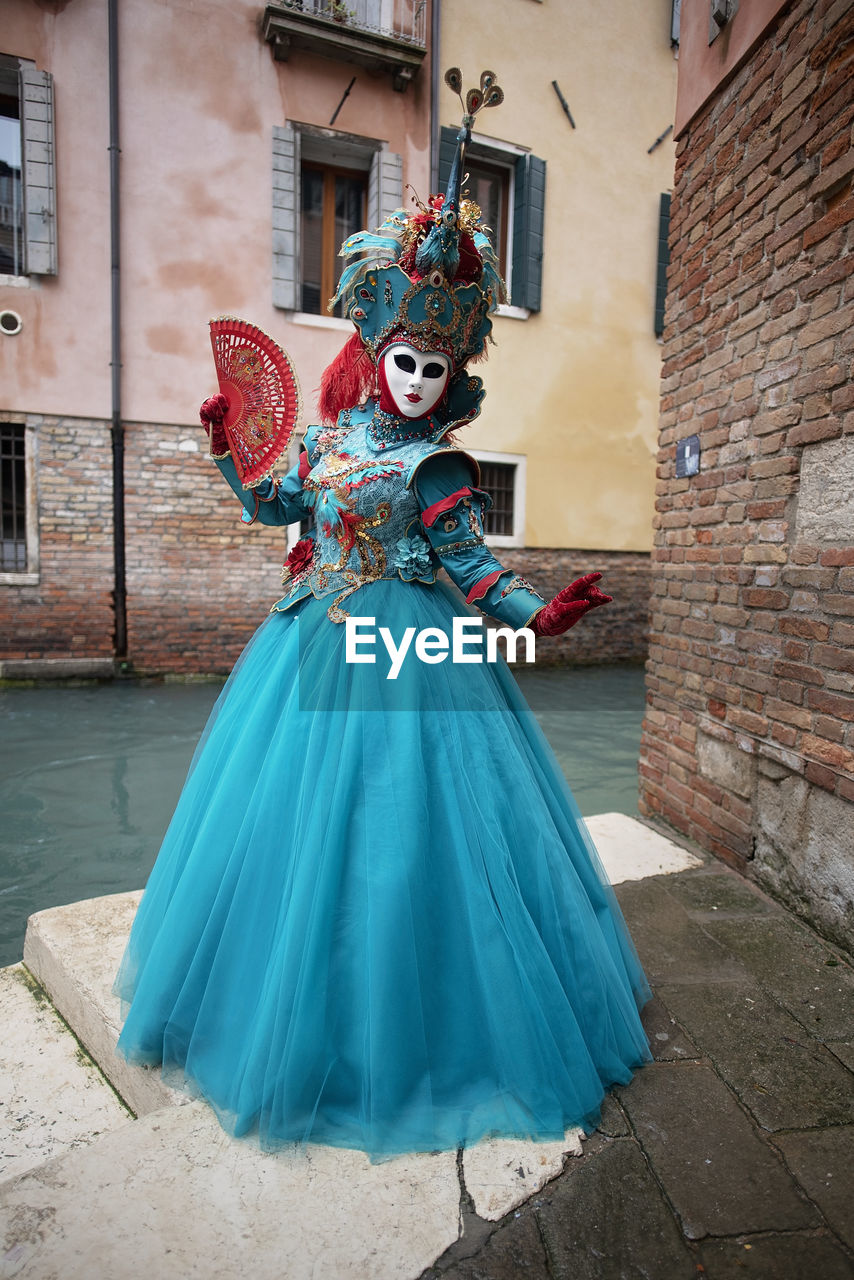 Portrait of woman in carnival costume standing by canal in city