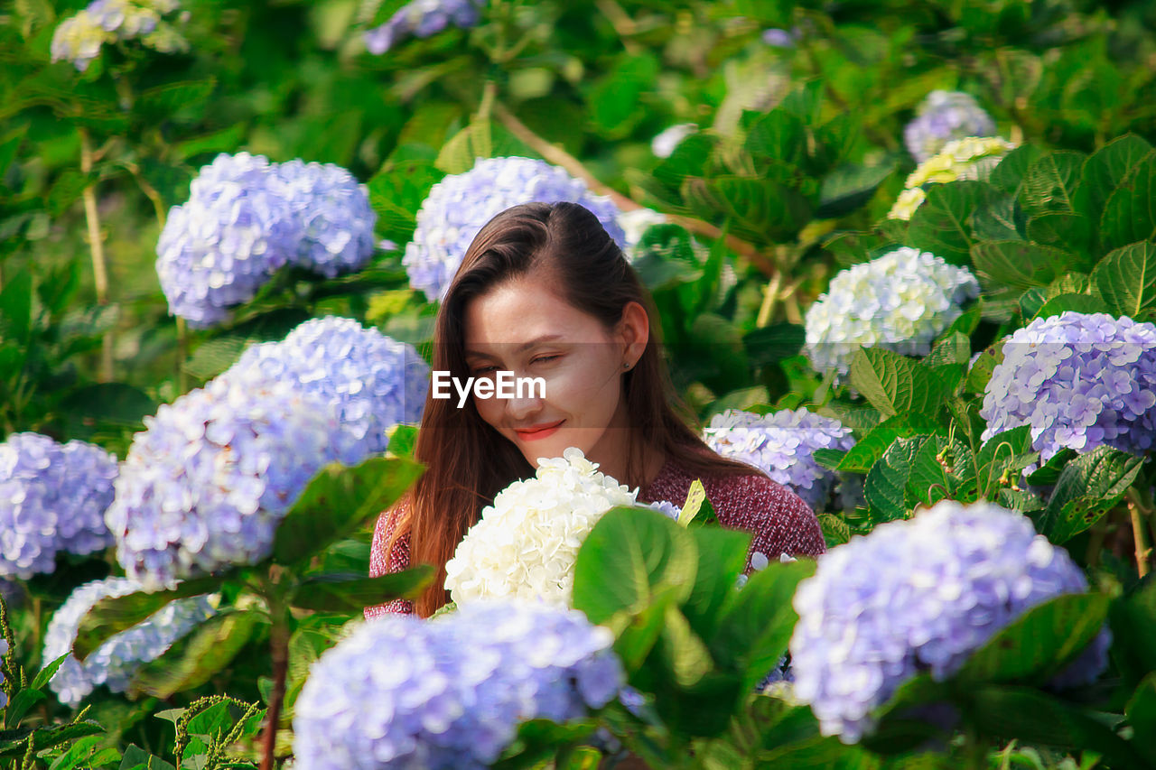 PORTRAIT OF YOUNG WOMAN WITH PURPLE FLOWERS