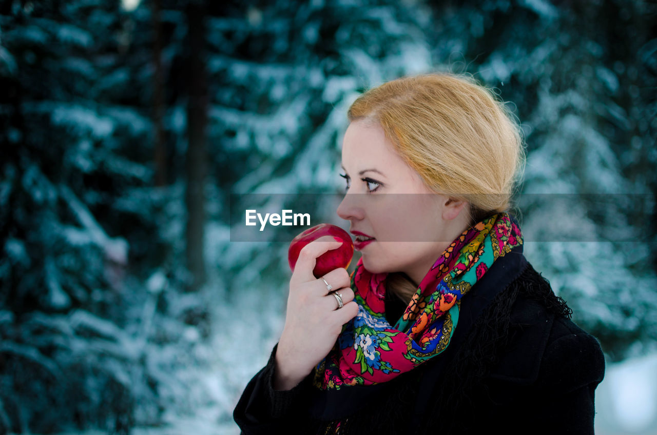 Woman holding apple while standing outdoors