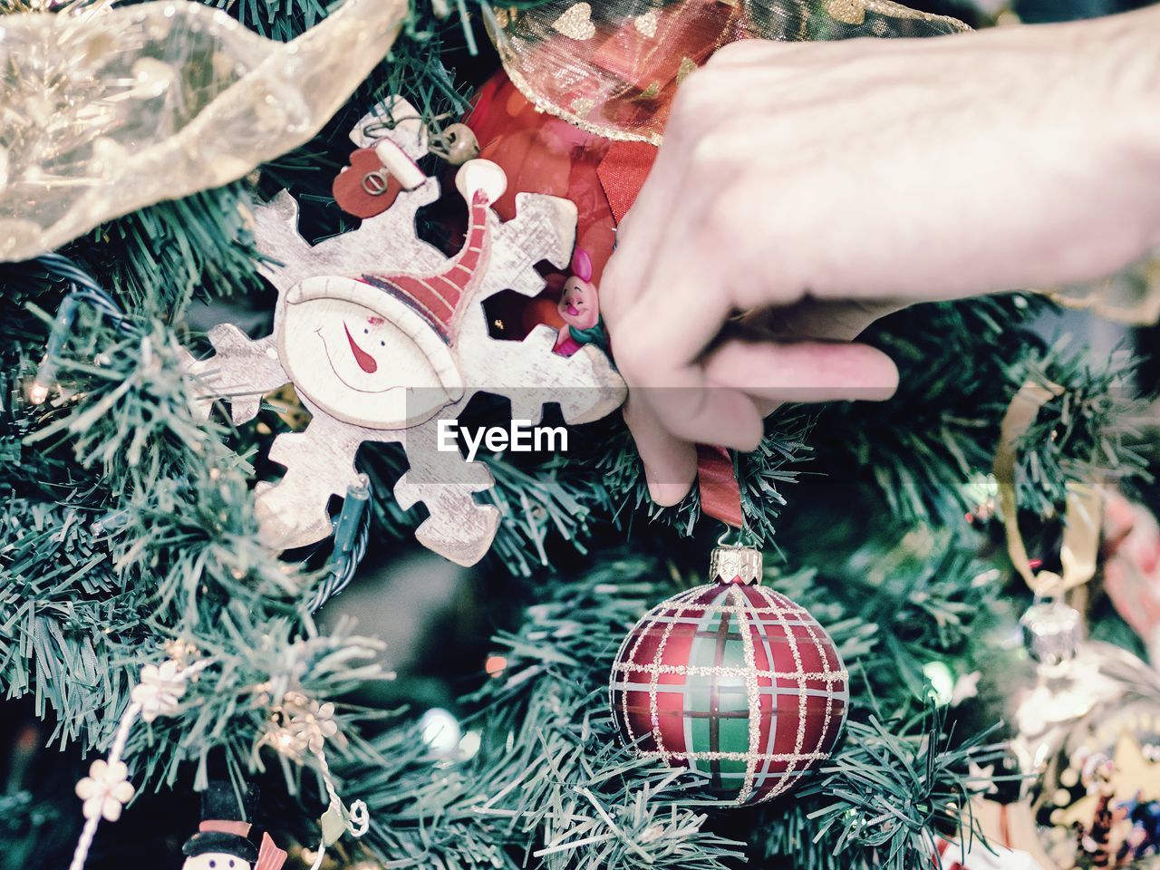 Cropped hand of person decorating christmas tree