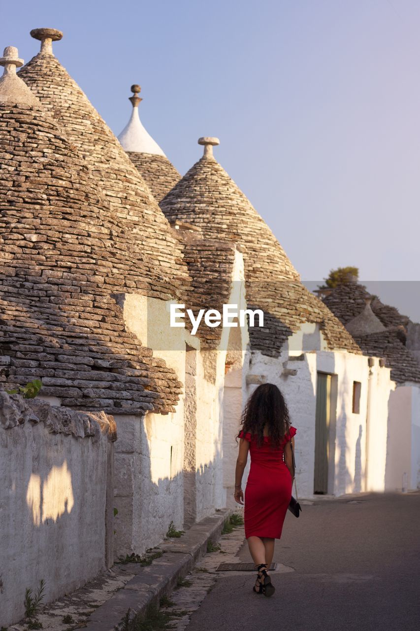 Rear view of woman walking in alley against building