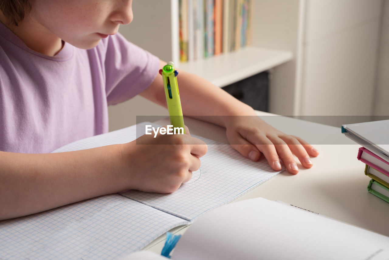 Close-up of children's hands. left-hander writes in a notebook on the table. left handed child. 