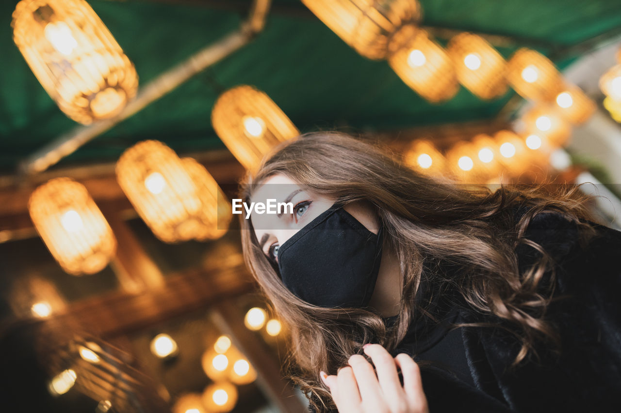 PORTRAIT OF YOUNG WOMAN WITH ILLUMINATED LIGHTING EQUIPMENT