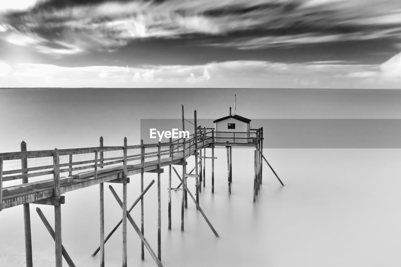 water, sky, black and white, cloud, sea, monochrome photography, monochrome, nature, architecture, built structure, pier, scenics - nature, beauty in nature, tranquility, no people, beach, environment, horizon, outdoors, horizon over water, wood, tranquil scene, land, landscape, day, transportation, travel destinations, travel