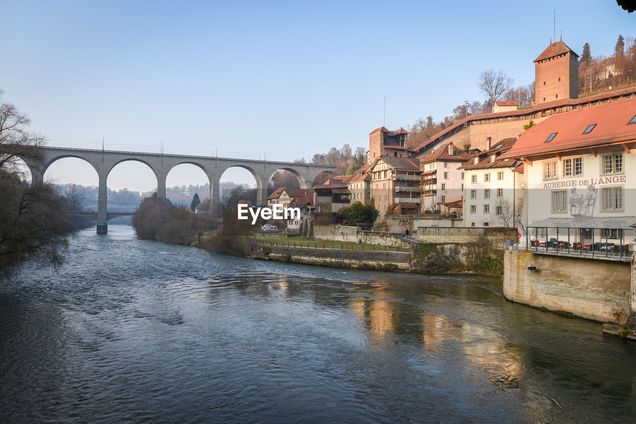 ARCH BRIDGE OVER RIVER BY BUILDINGS AGAINST SKY