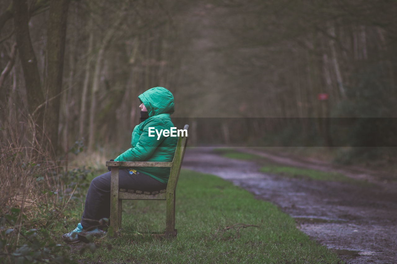 Woman sitting on bench by road