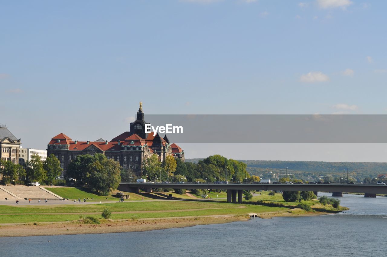 VIEW OF BUILDINGS BY RIVER AGAINST SKY IN CITY