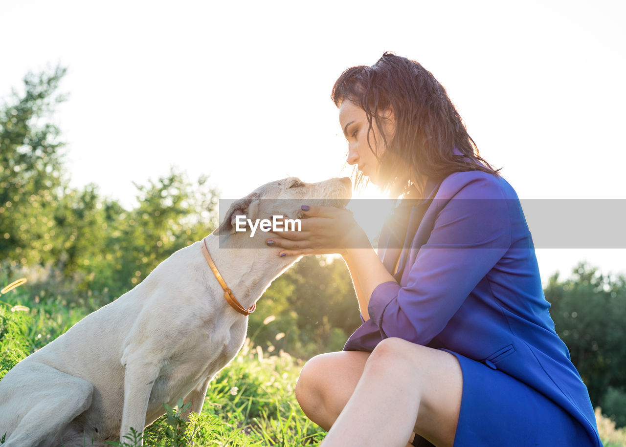 Side view of woman with dog outside in sunset 