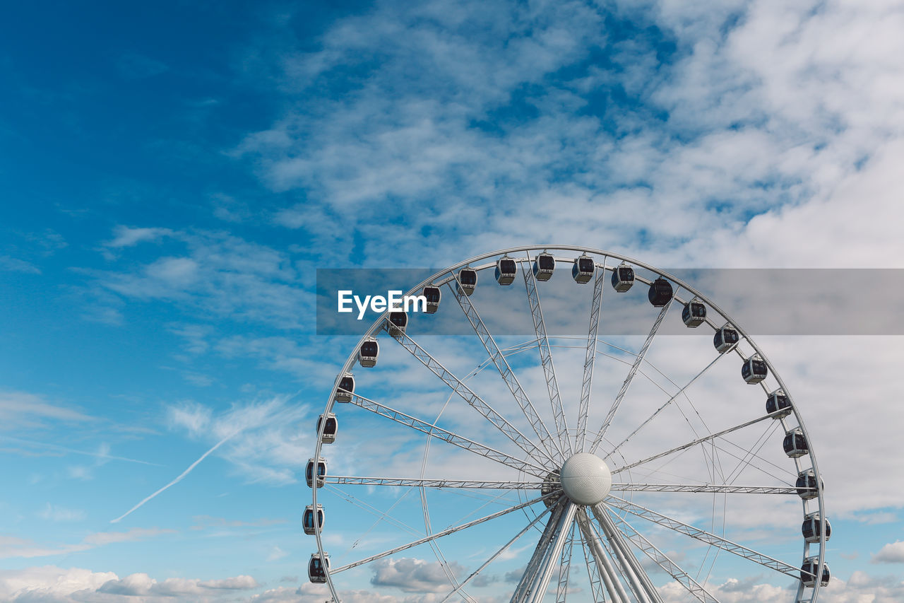 Low angle view of ferris wheel against cloudy sky