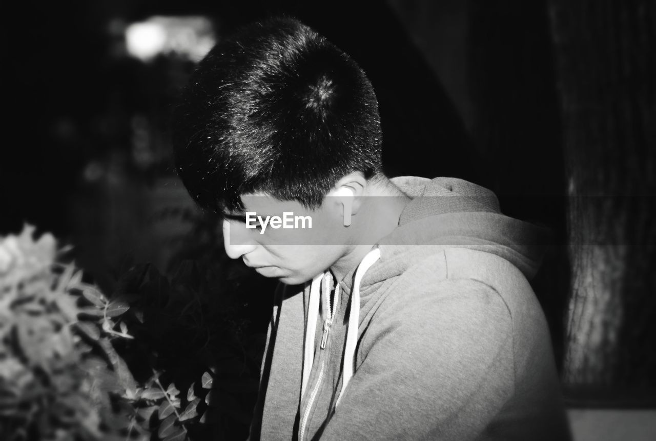 SIDE VIEW OF YOUNG MAN LOOKING AWAY OUTDOORS