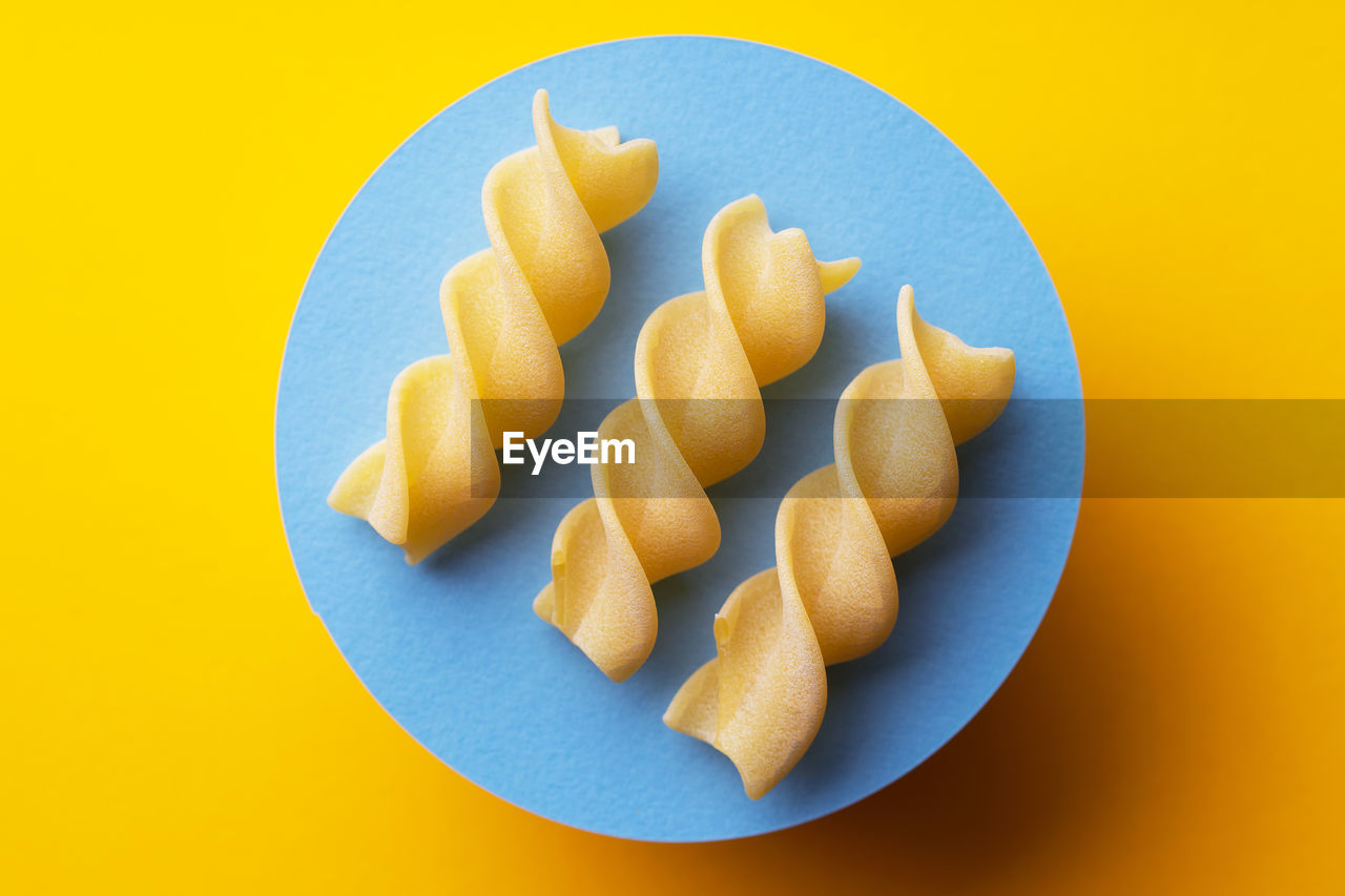 HIGH ANGLE VIEW OF FRESH ORANGE AND YELLOW EGGS AGAINST WHITE BACKGROUND