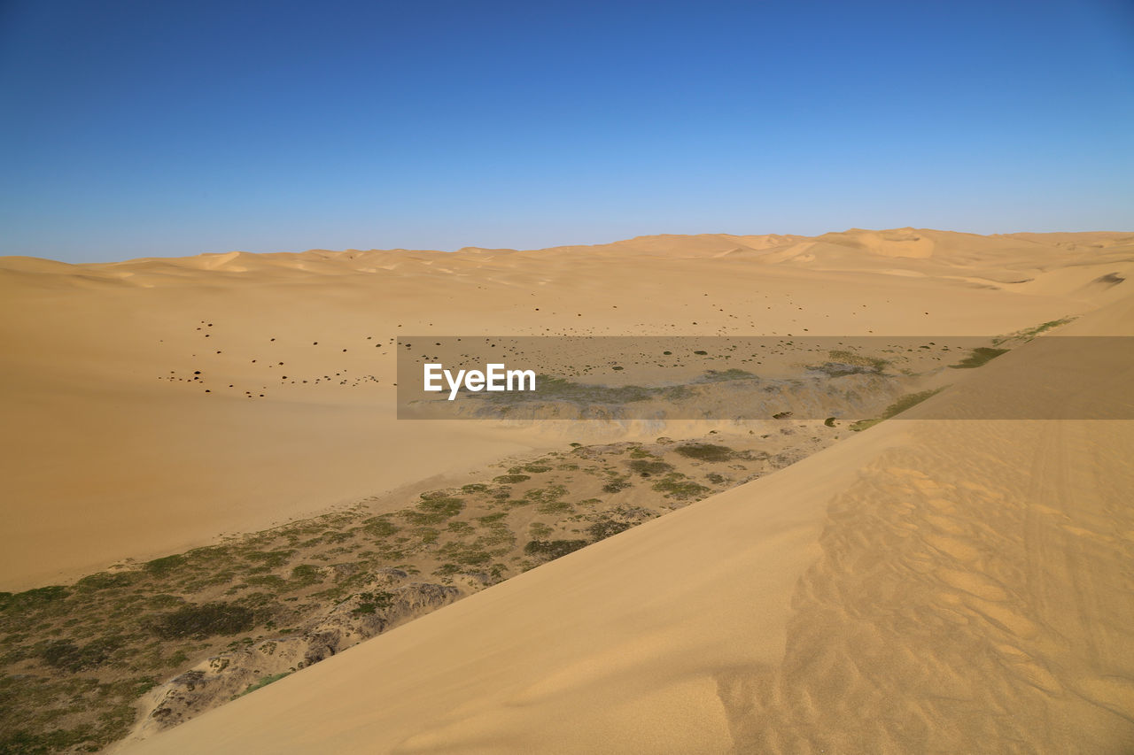 Scenic view of desert against clear blue sky