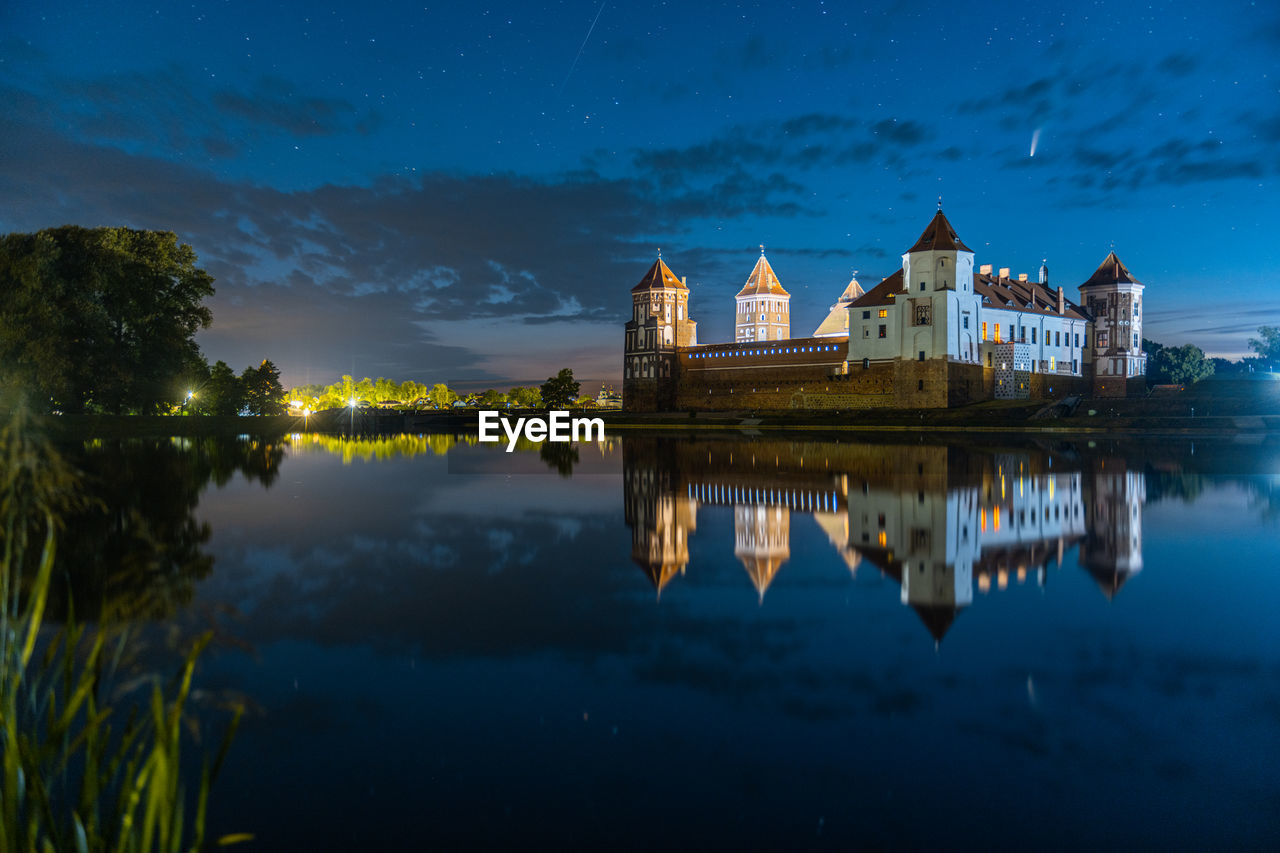 Comet neowise in a night landscape. mir castle in belarus. beautiful landscape with stars and comet