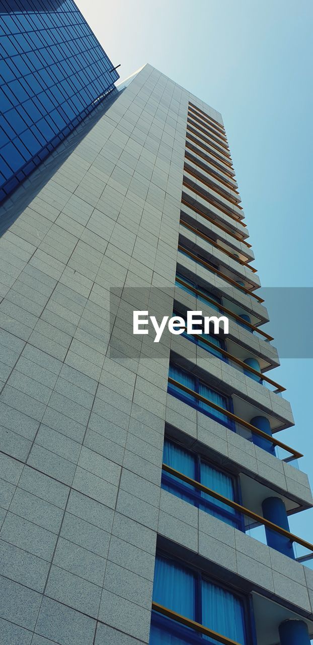 LOW ANGLE VIEW OF MODERN GLASS BUILDING AGAINST SKY