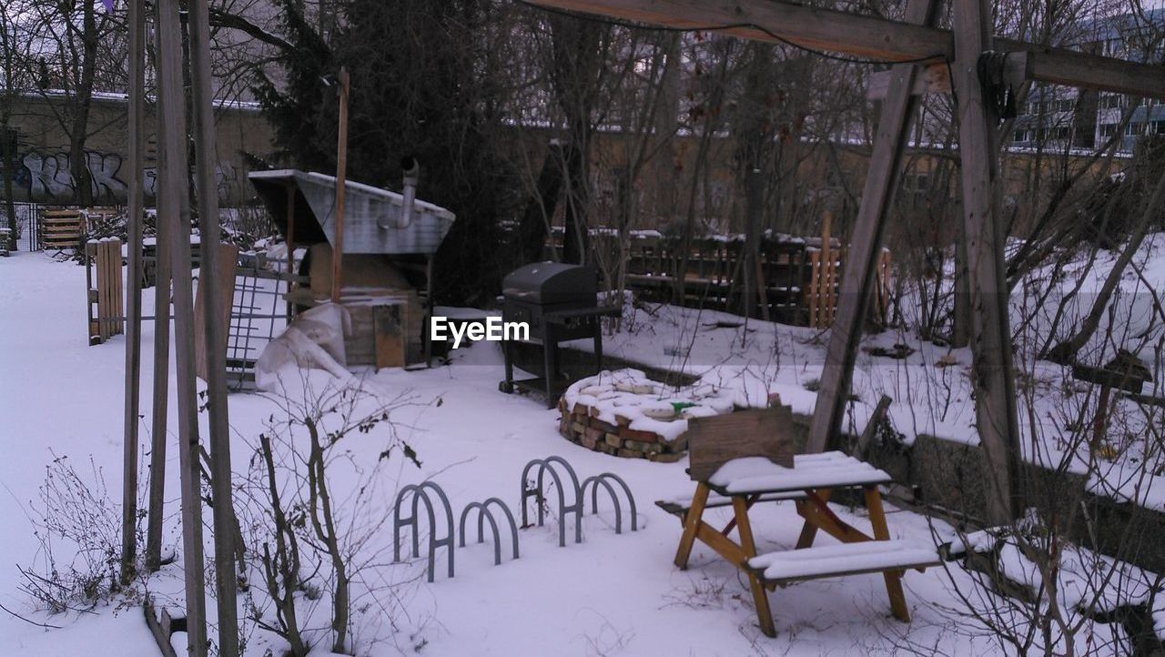 EMPTY CHAIRS AND TABLES ON SNOW COVERED FIELD
