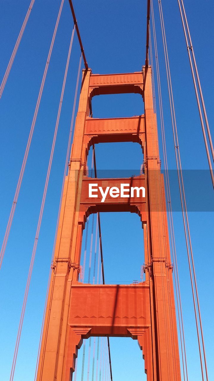 LOW ANGLE VIEW OF RED METALLIC STRUCTURE AGAINST BLUE SKY