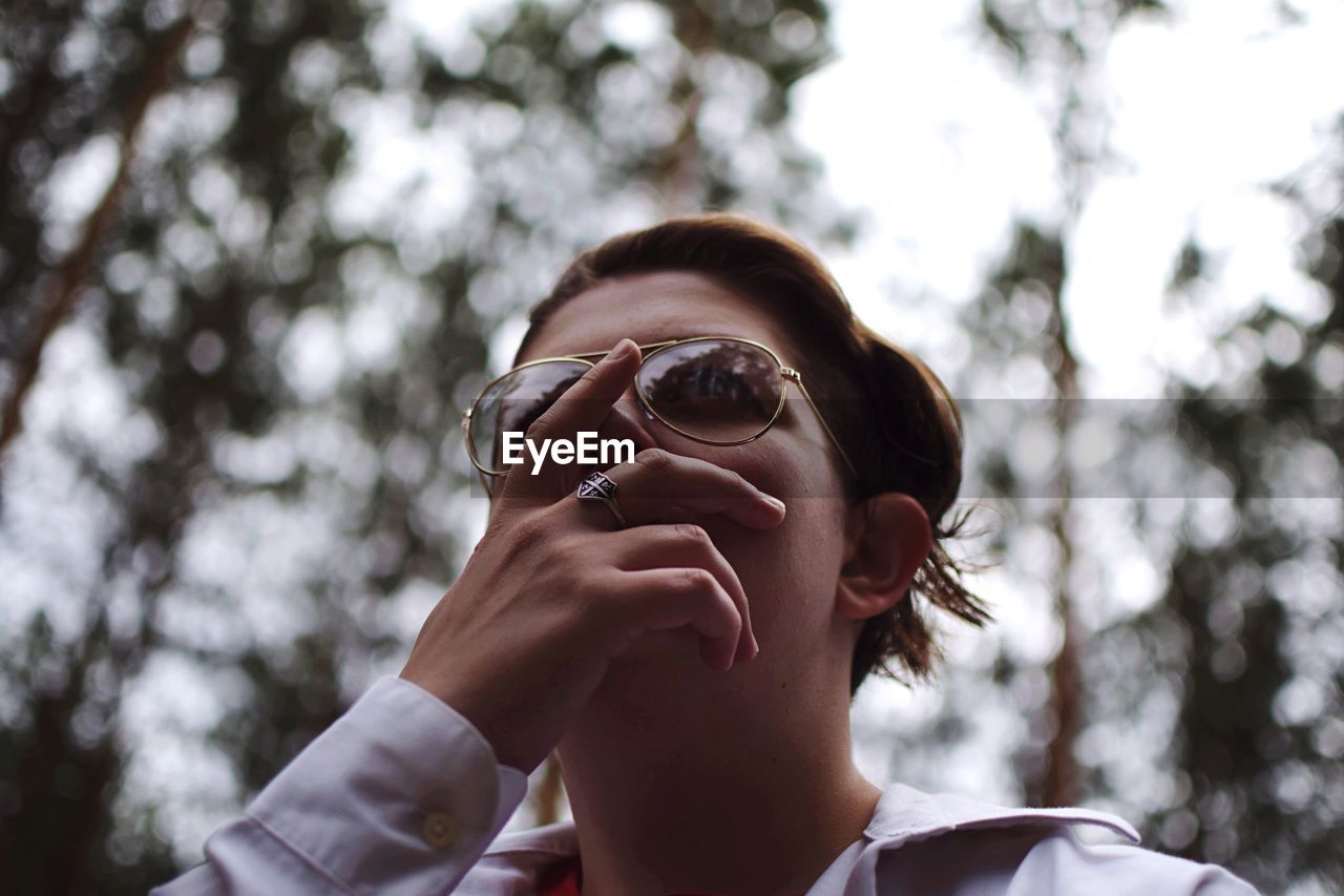 Low angle view of woman wearing sunglasses in forest