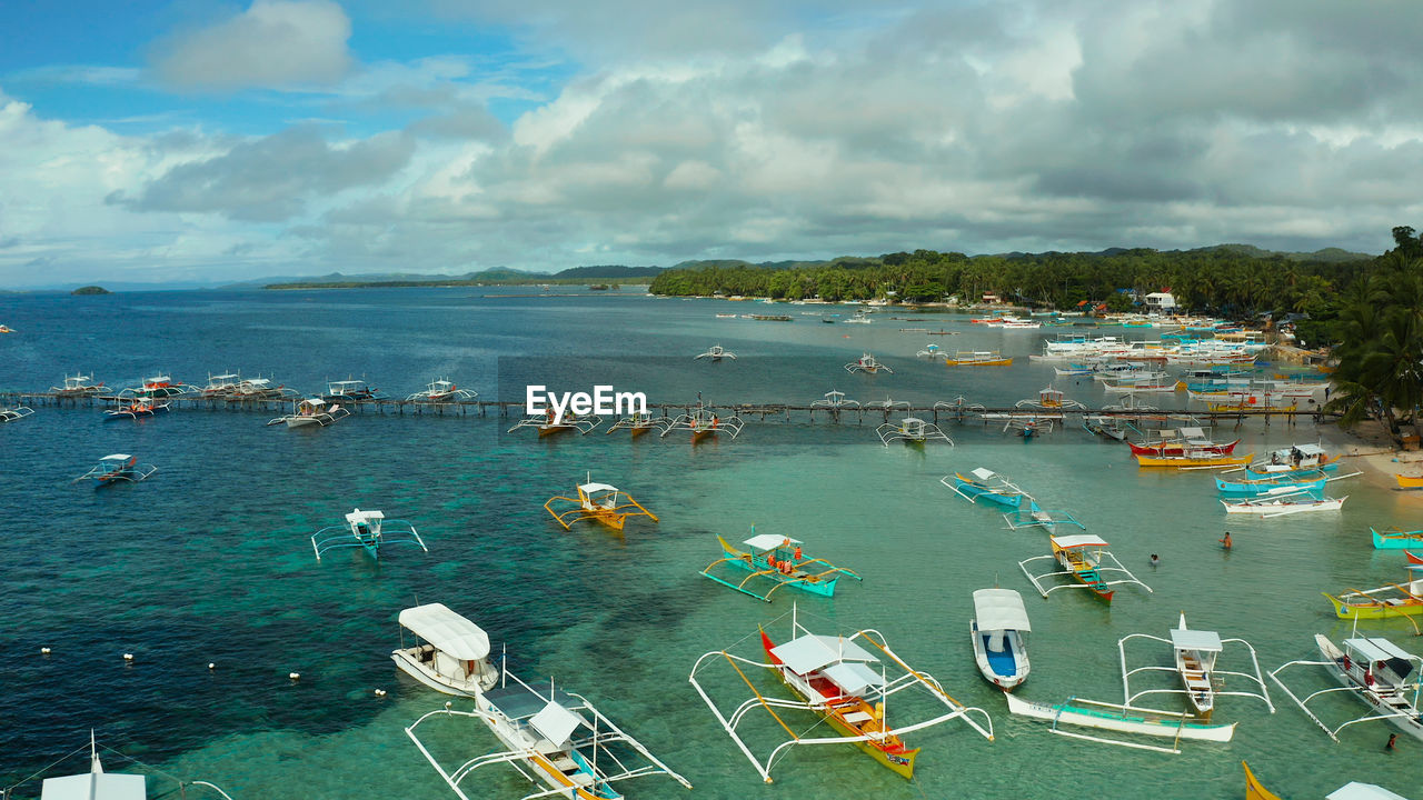 Boats waiting for tourists on a tropical beach in blue water, aerial view. 