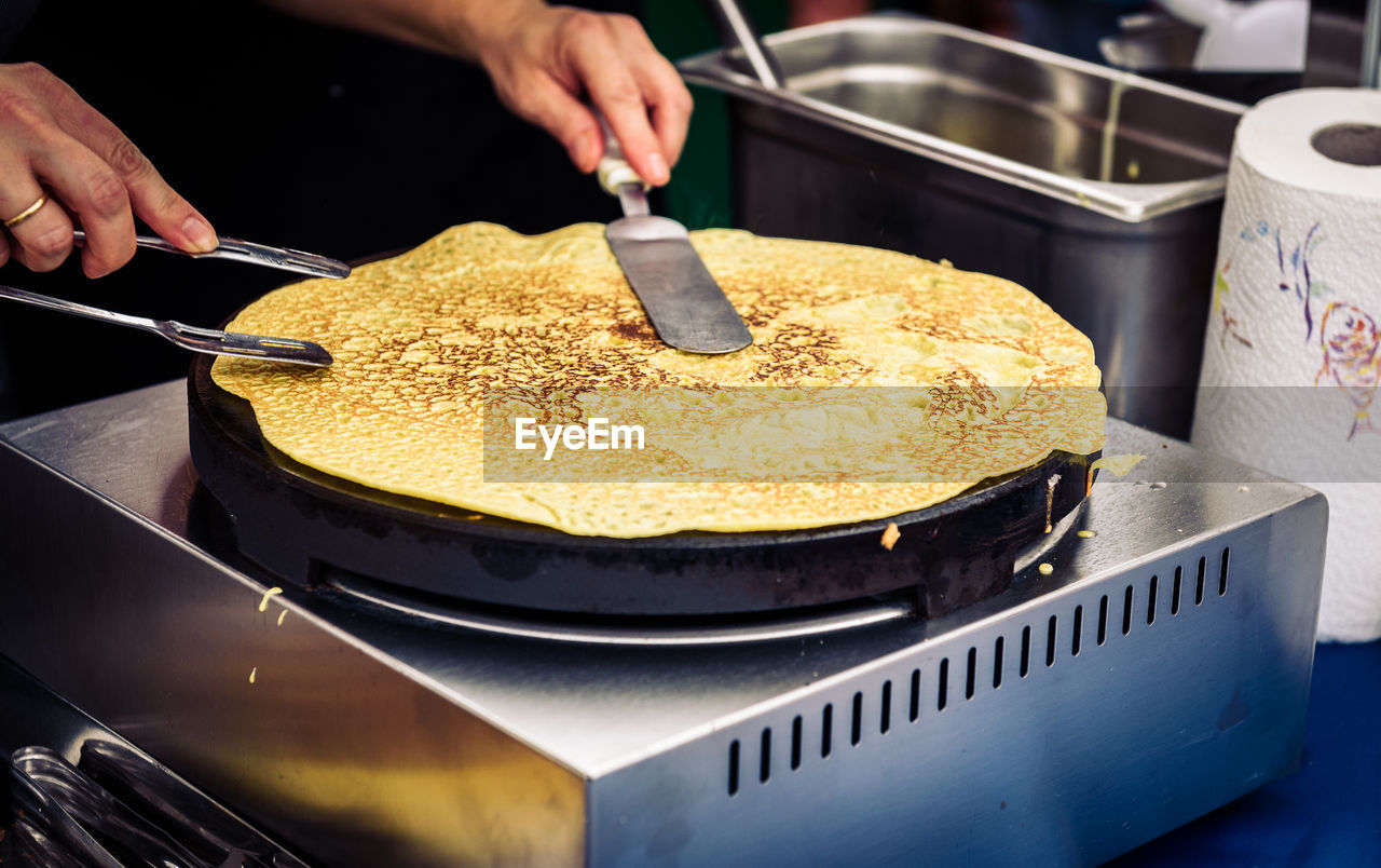 Close-up of cropped hands making pancake in kitchen