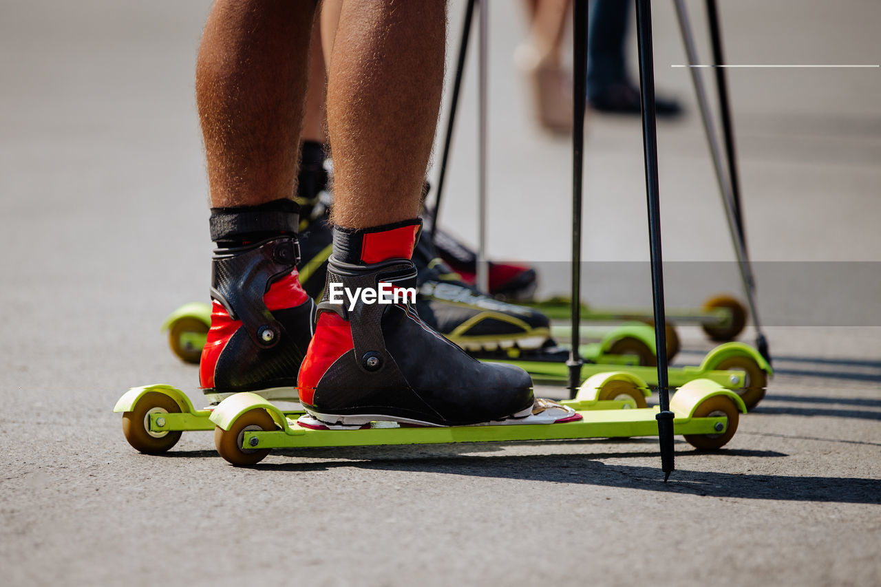 Tanned legs of skier athlete in roller ski and poles