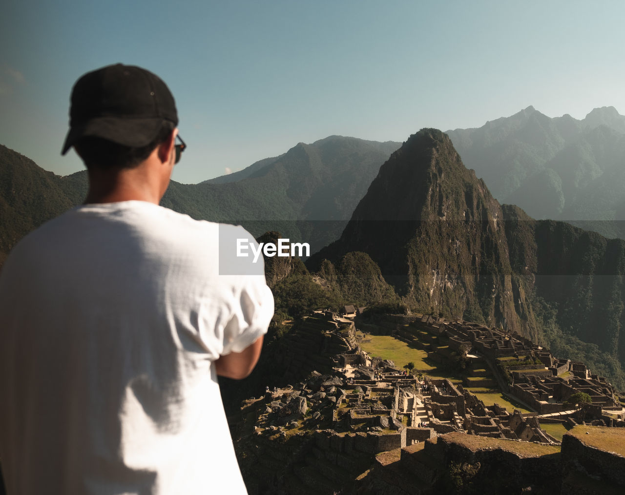 Rear view of man looking at mountains against sky