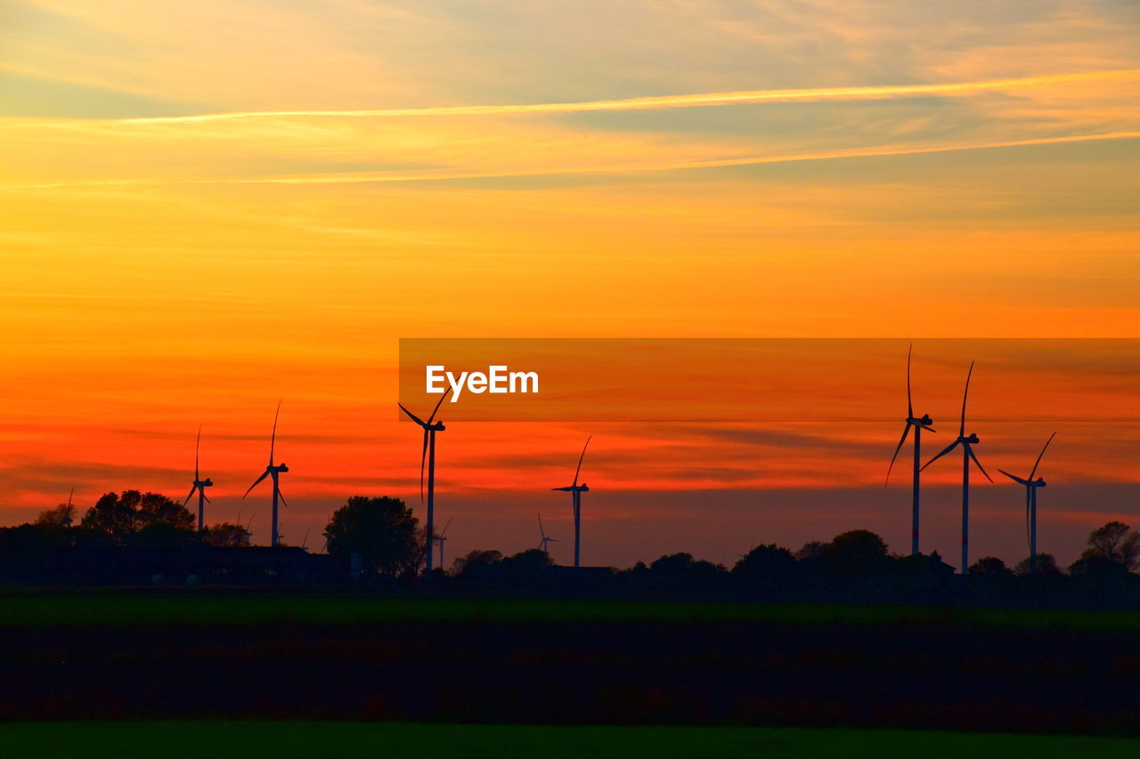 Silhouette of wind turbines on green field during sunset