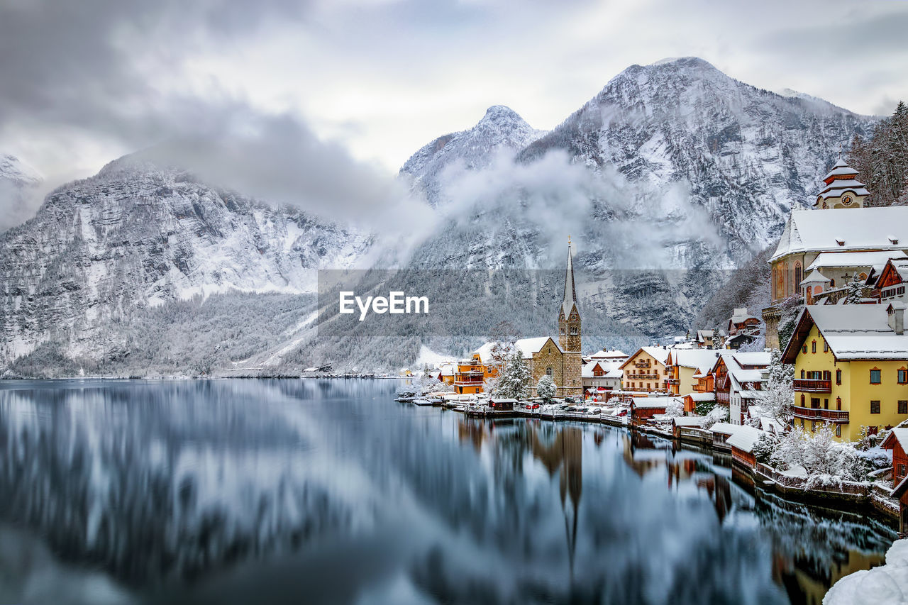 Scenic view of houses by snowcapped mountains and lake against sky