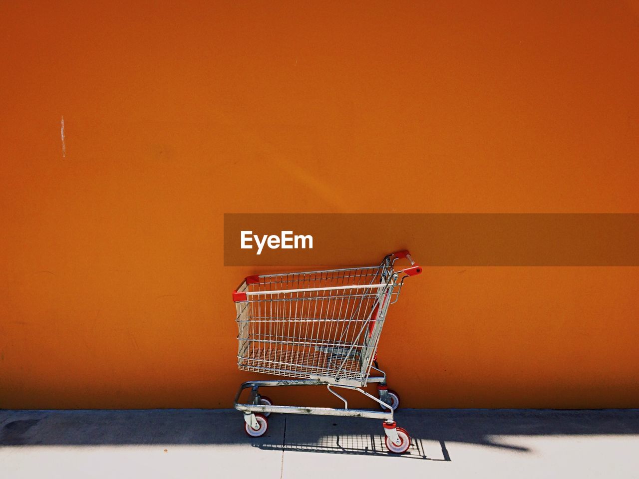 Shopping cart against orange wall