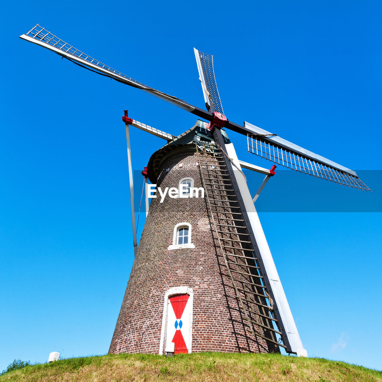 Low angle view of traditional windmill against blue sky