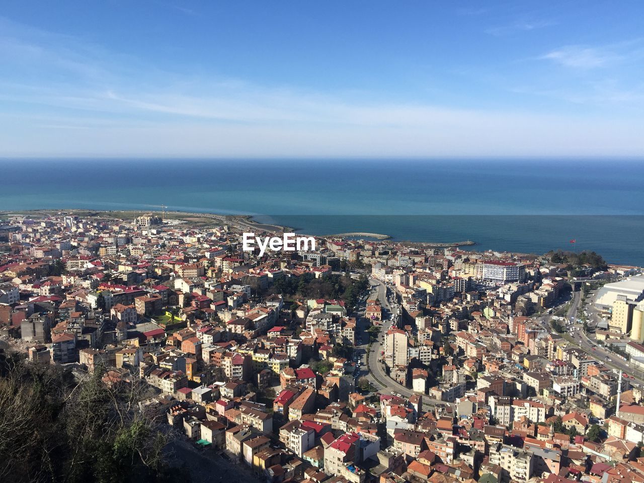 High angle view of townscape by sea against blue sky