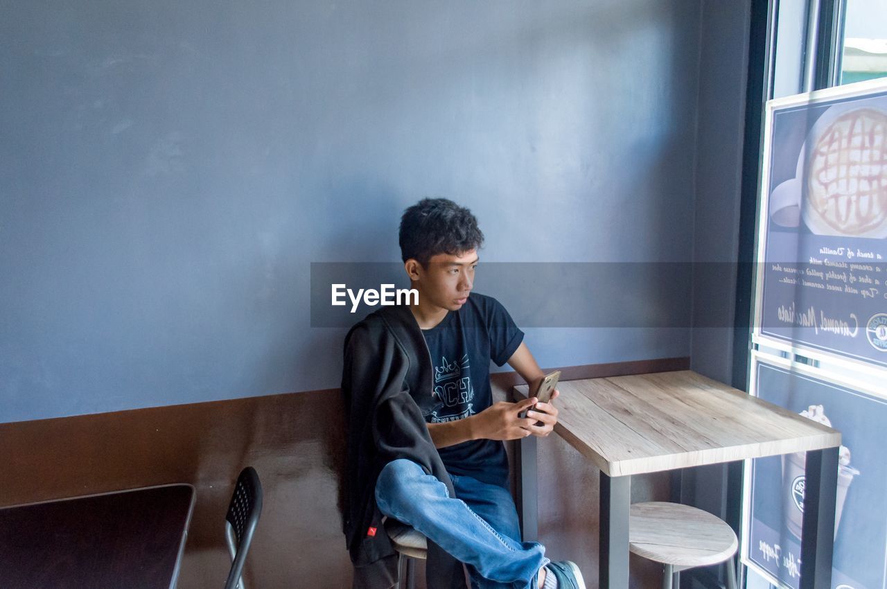 Young man using mobile phone while sitting in cafe