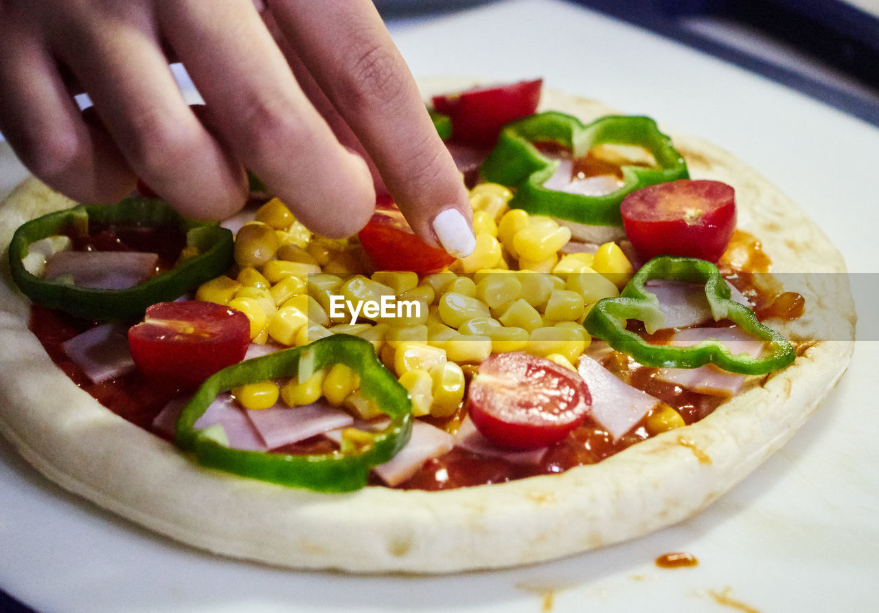 Close-up of hand preparing pizza in plate