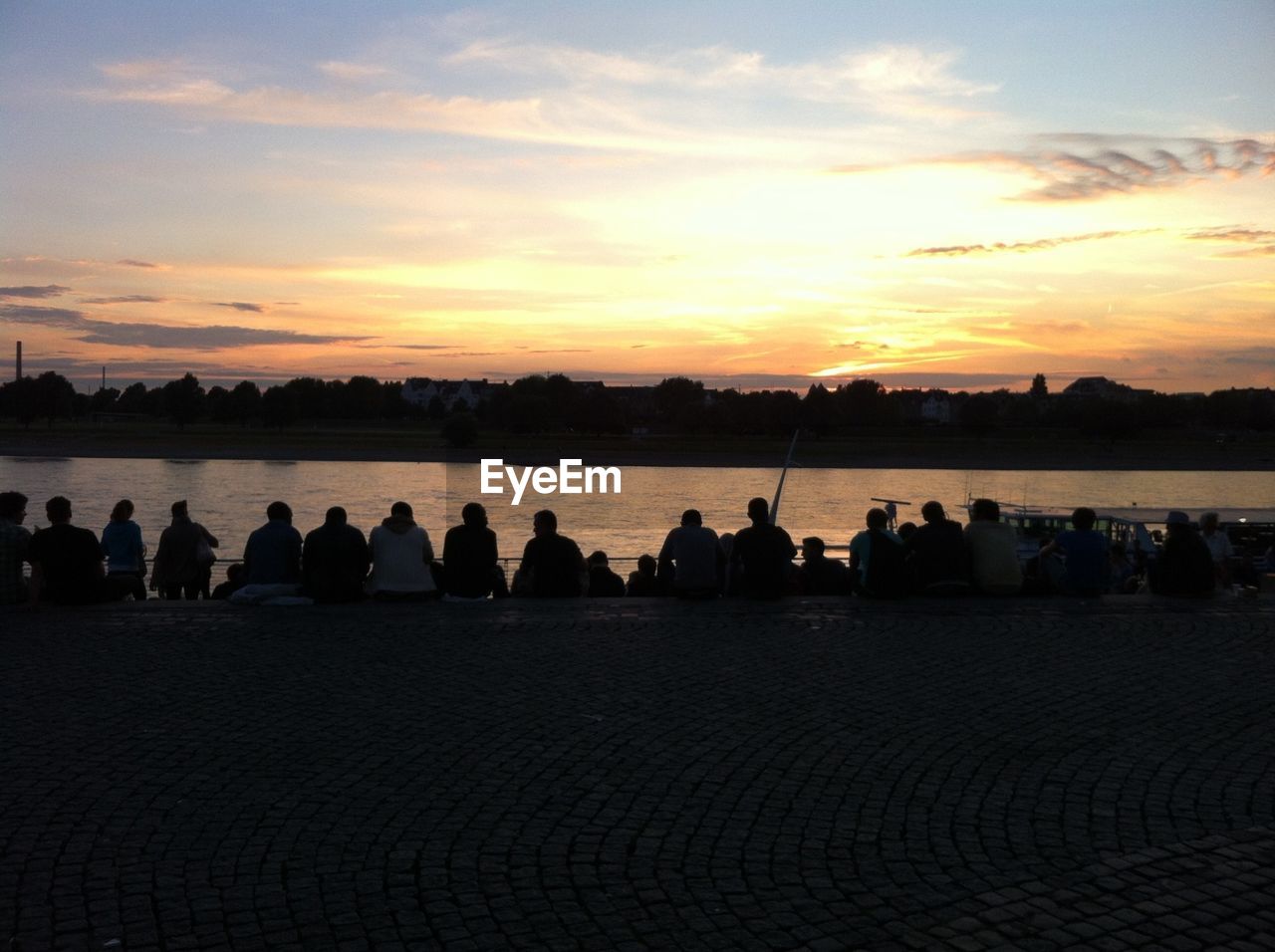 Large group of people watching sunset over river