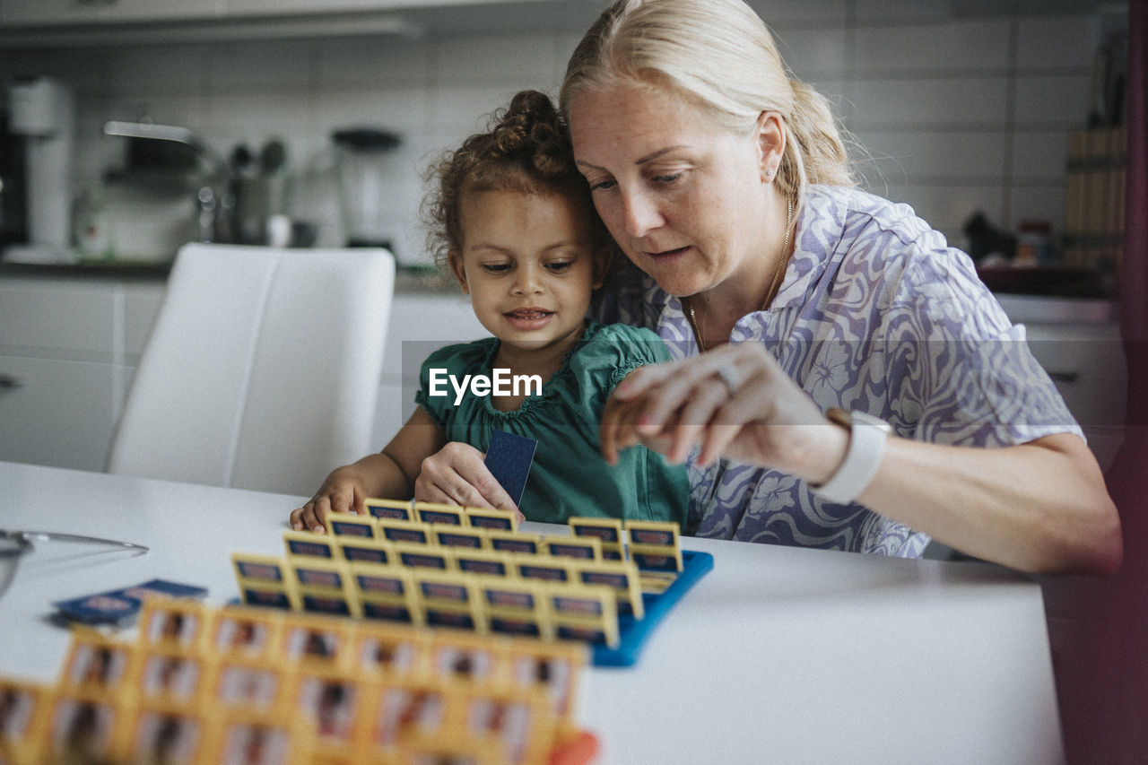 Mother and daughter spending time together playing game at home