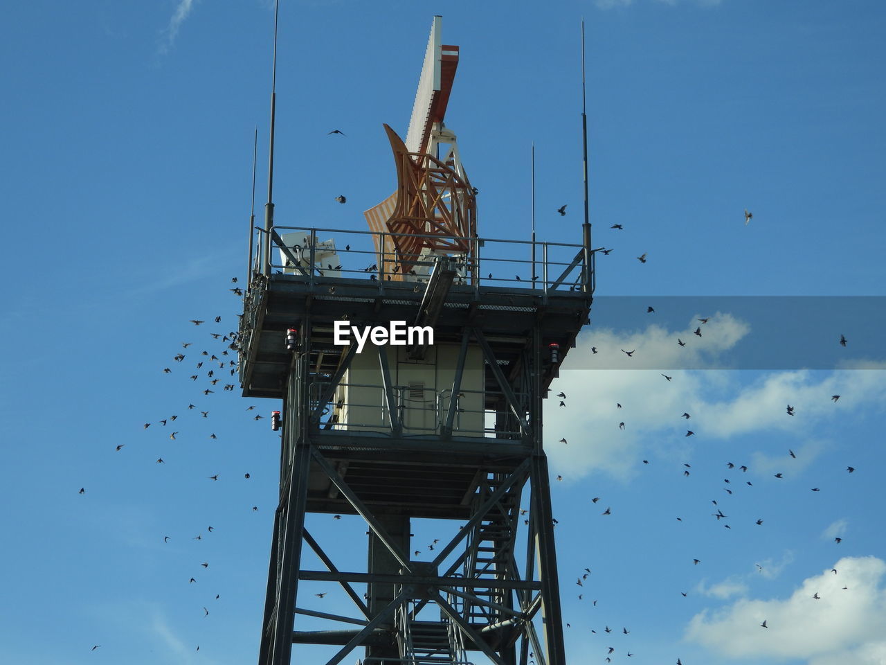 Low angle view of airport radar tower with birds