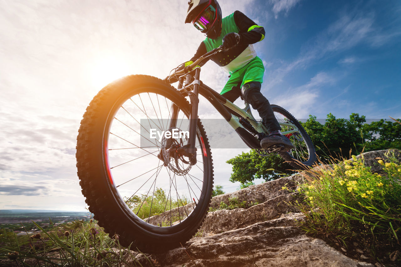 Mountain biker on a stone forest path. a cyclist rides on a rock. dinehill rider on his mountain