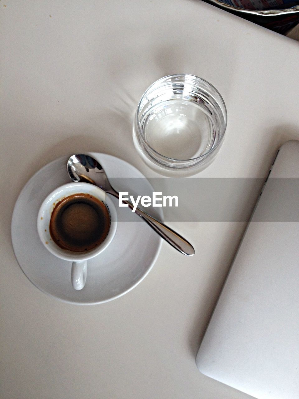 High angle view of coffee cup by drinking glass on table