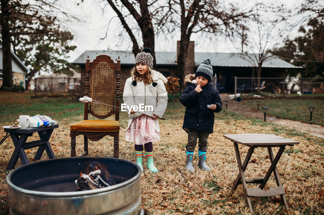 Young boy and girl roasting marshmallows for smores in back yard