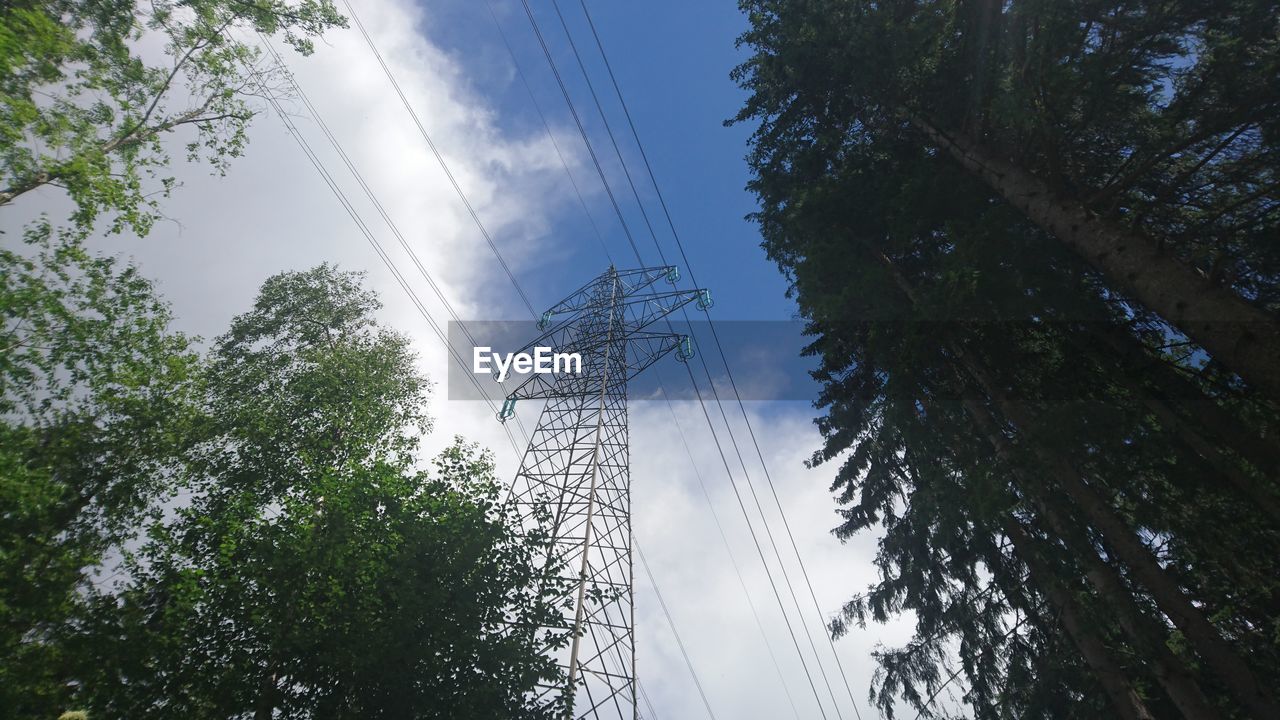 Low angle view of electricity pylon and trees against sky