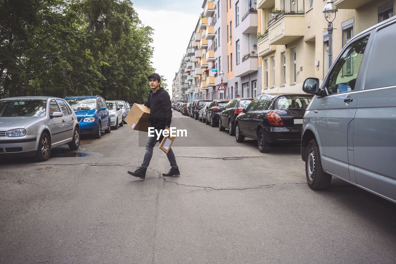 Delivery man with package walking on street in city