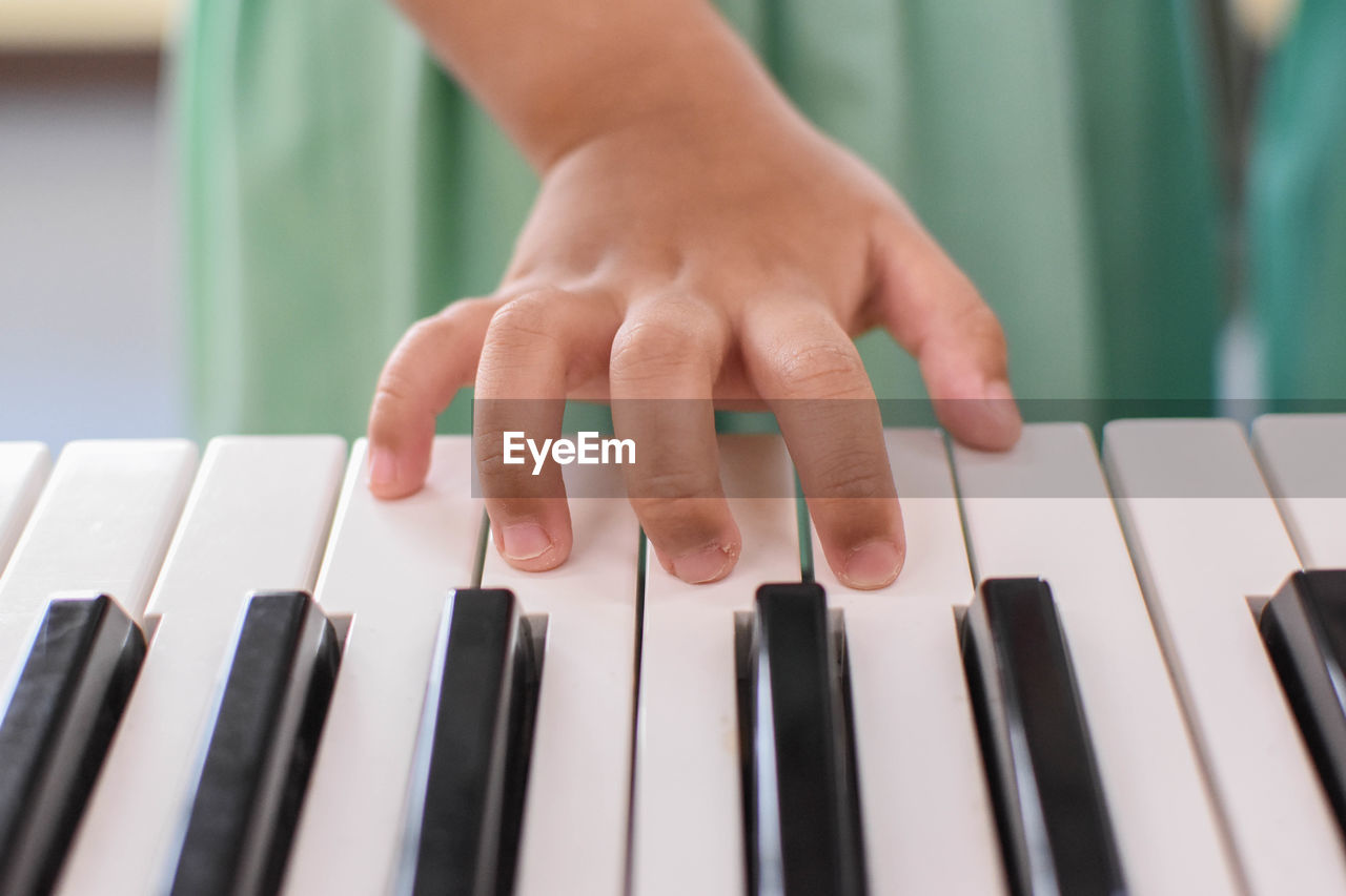 Cropped hand of child playing piano