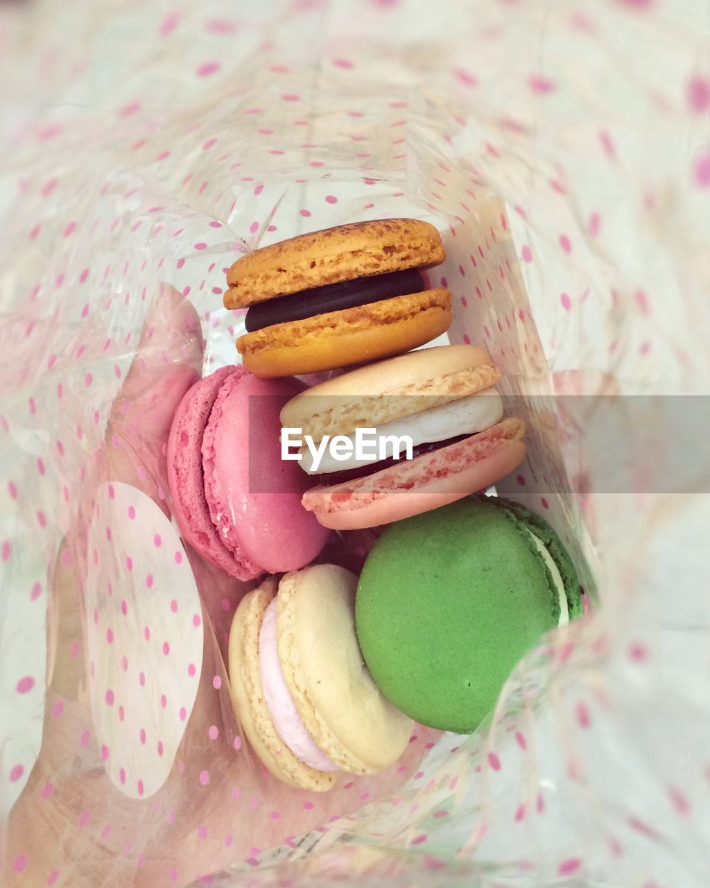 Double exposure of hand with fresh colorful macaroons in spotted bag