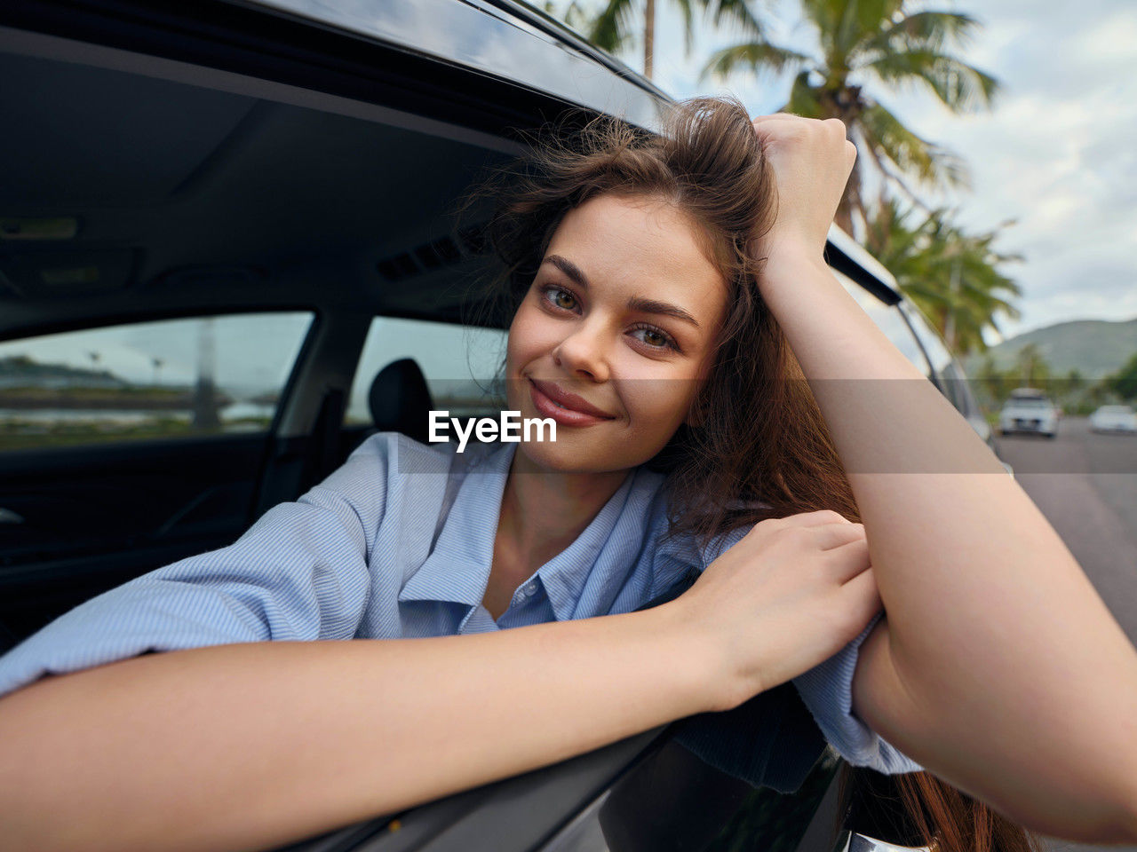 portrait of young woman sitting on car